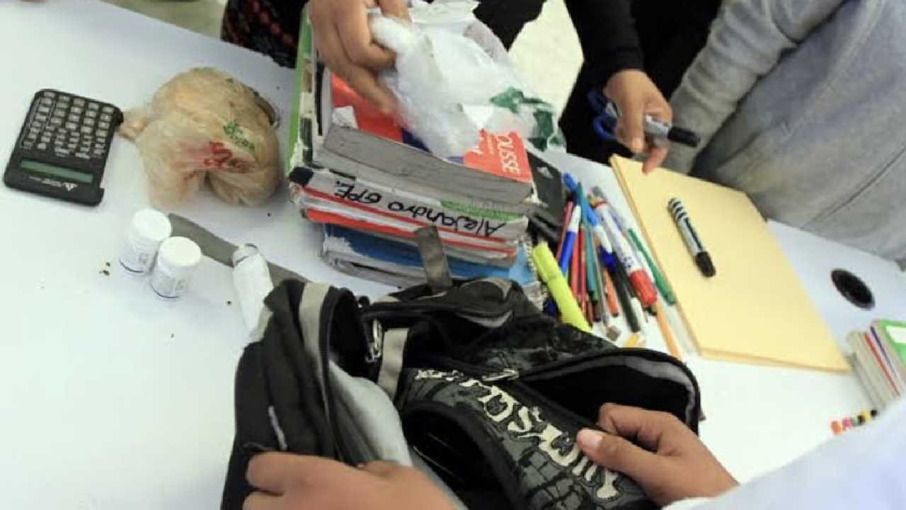 School backpack inspection showing confiscated knives and replica firearms in Quintana Roo