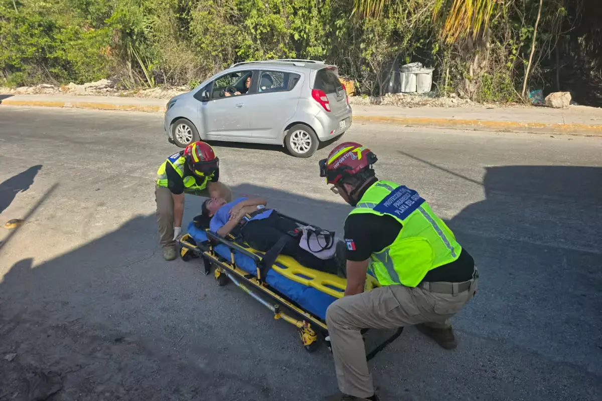 Paramedics attend to an injured woman on the pavement after a collision between a mototaxi and a motorcycle in Playa del Carmen