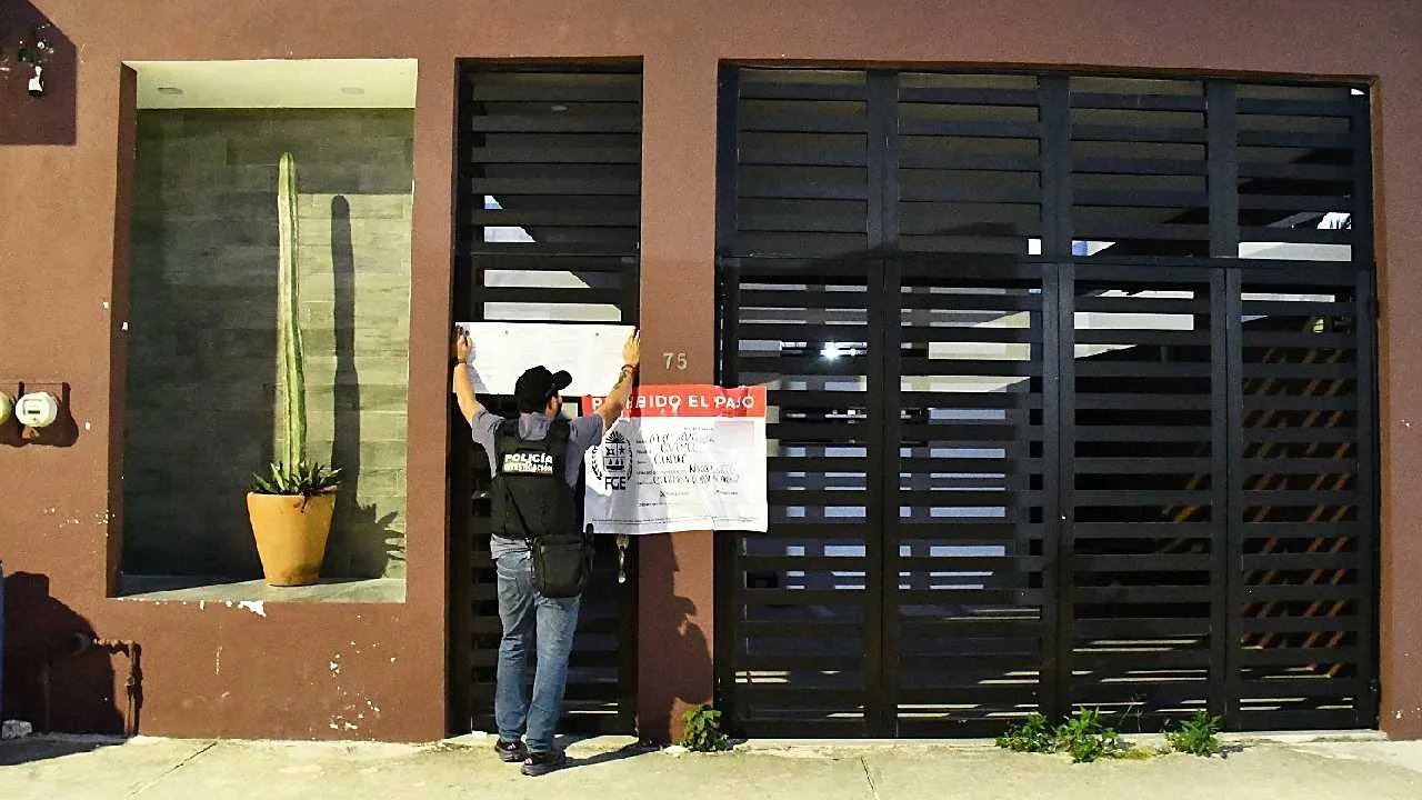Police officers stand outside a building with evidence markers during a drug raid in Cozumel, Quintana Roo.