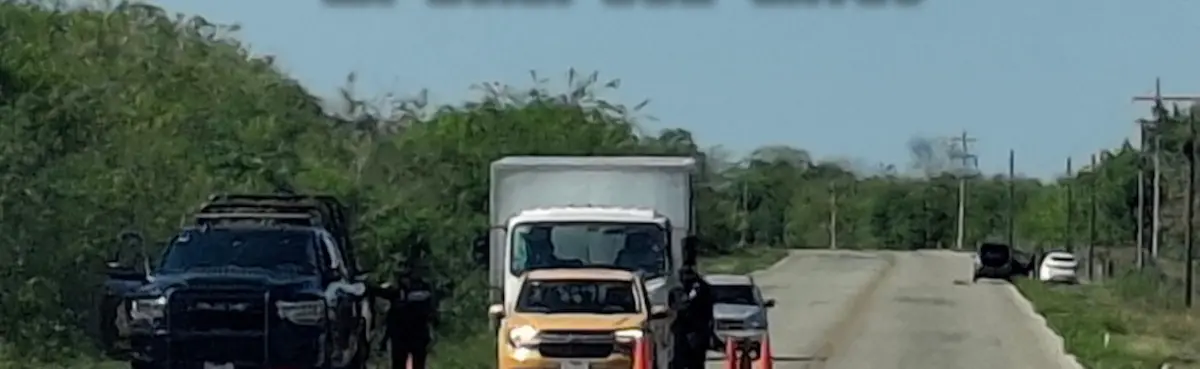 Police vehicles and officers at the entrance of a ranch during a raid on the Tizimín-Calotmul highway in Yucatán, Mexico.