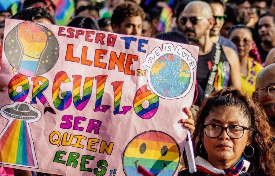 LGBTQ+ community members with rainbow flags at a Pride march in Quintana Roo