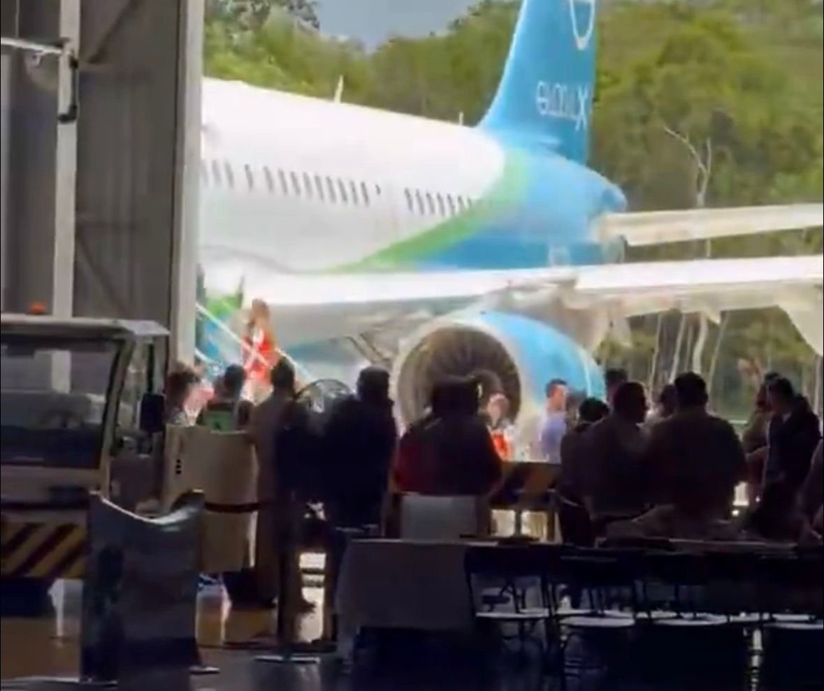 A plane carrying Mexican repatriates on the tarmac at Tulum International Airport with security personnel nearby