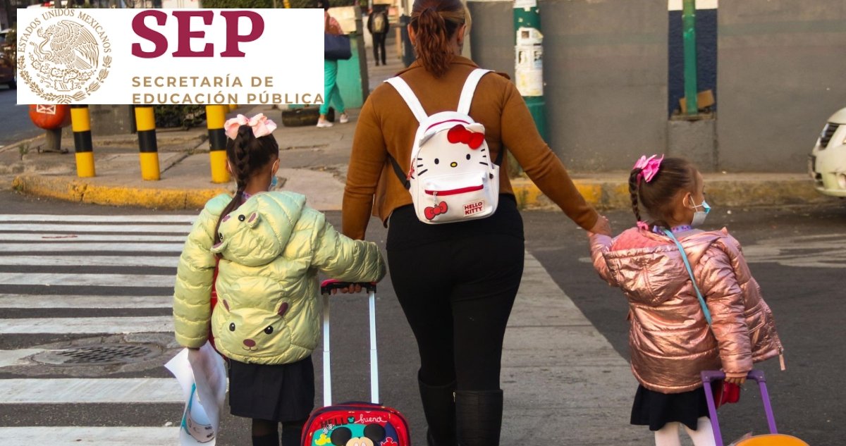 A mother walks with two young girls holding hands and pulling wheeled backpacks across a crosswalk. The scene is set in an urban environment with pedestrians in the background.$# CAPTION