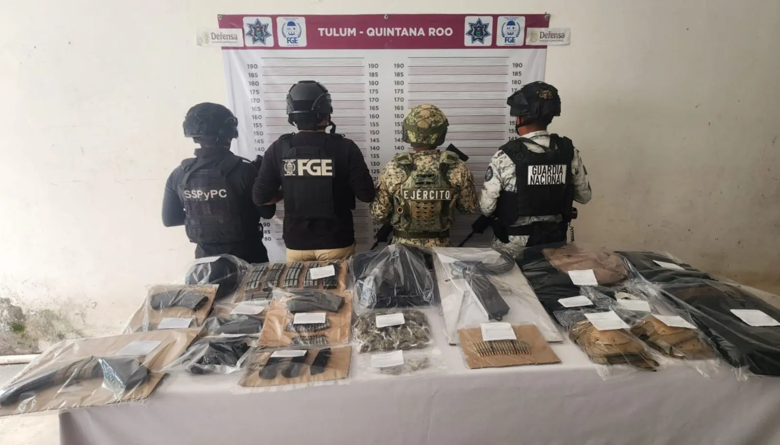 Table covered with seized rifles and handguns displayed by authorities in Tulum