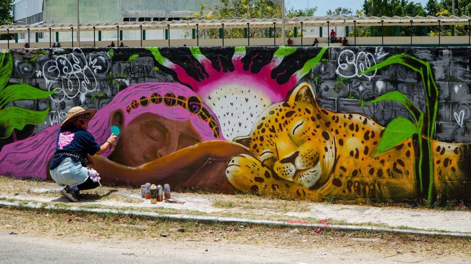 Colorful murals and graffiti covering a long wall at a sports complex in Valladolid, Yucatan