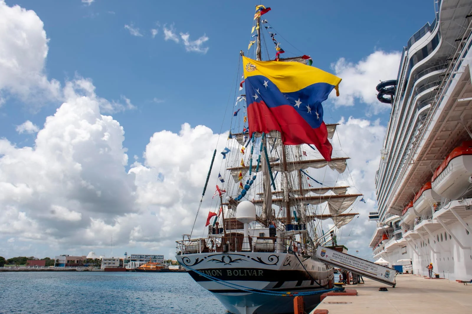 The Venezuelan training ship Simón Bolívar docked at Punta Langosta pier in Cozumel, with crew on deck and visitors on the pier.