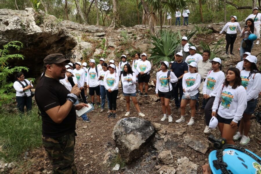 Volunteers in gloves and hats collecting trash around a cenote in Puerto Aventuras