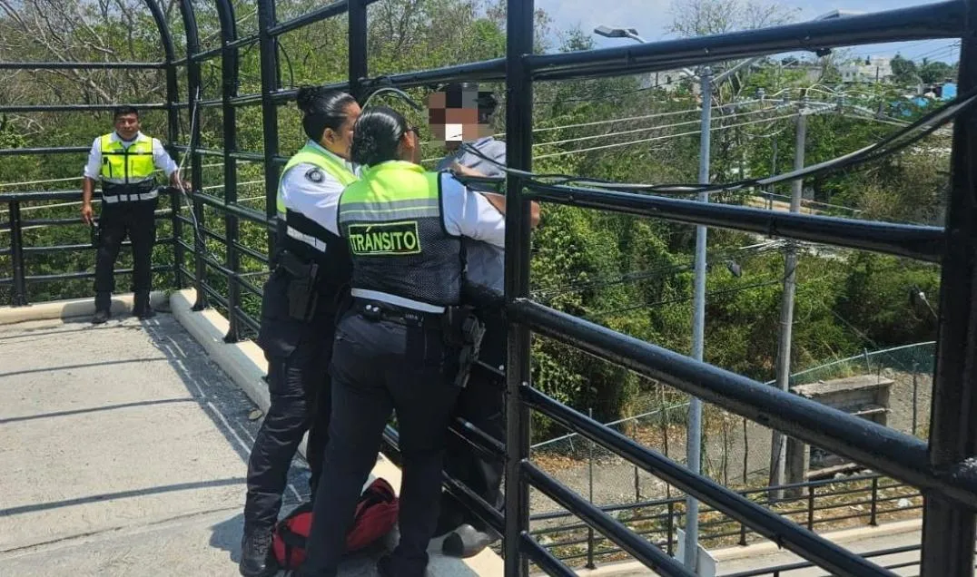 A woman being rescued by police officers on a bridge in Playa del Carmen