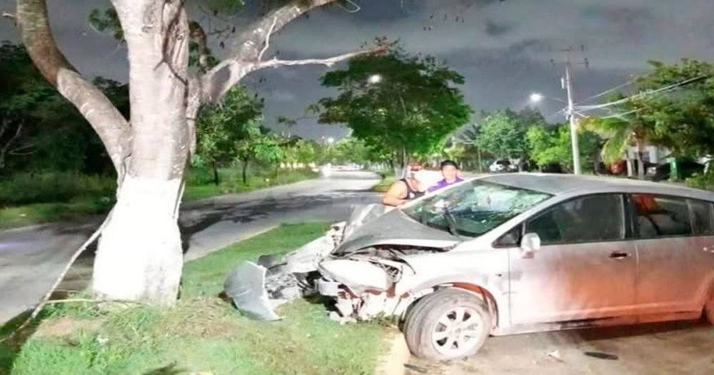 A damaged car abandoned after crashing into a tree on a Cancun avenue