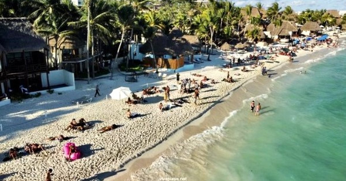 Aerial view of a white sand beach with turquoise water, swimmers, and tropical vegetation in Playa del Carmen