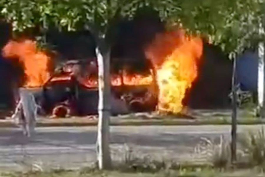 A burnt-out white van with fire damage on a road in Puerto Aventuras