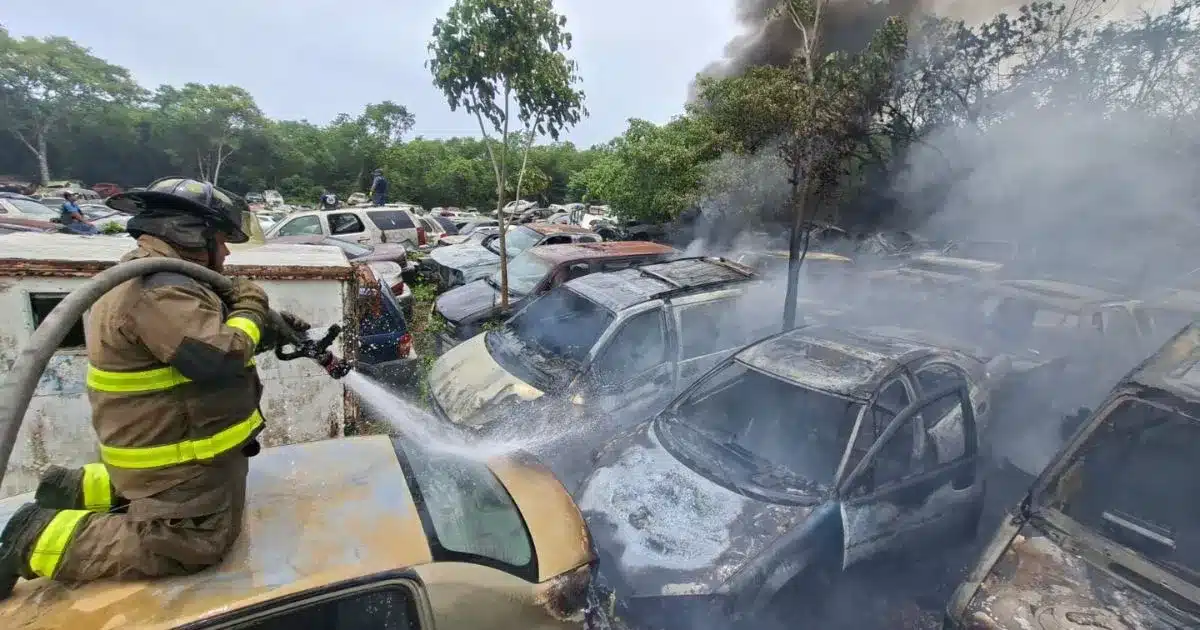Firefighters spraying water on a large fire at a recycling plant in Cancun