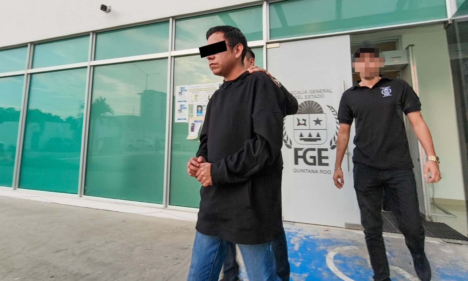 A man in handcuffs being led by police officers in Cancun