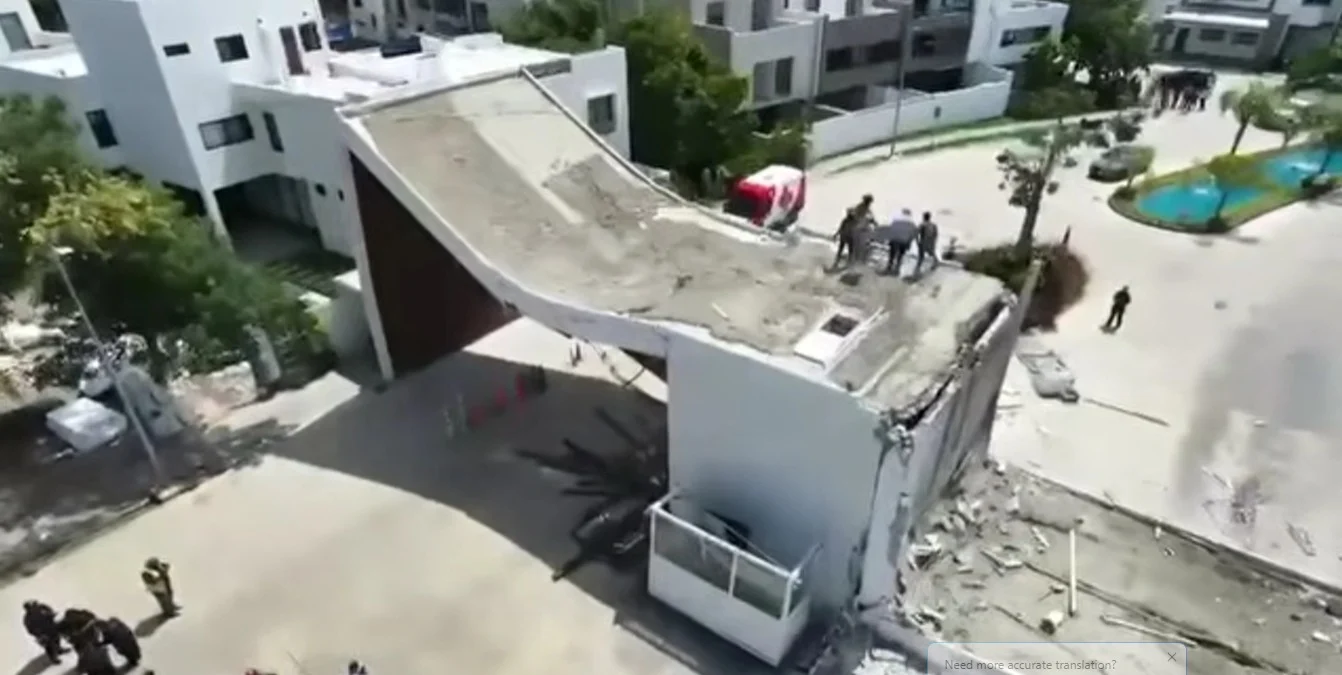 Debris from a collapsed structure at the entrance of Residencial Aqua in Cancun, with emergency personnel on site.