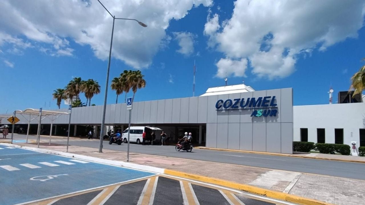 Exterior view of Cozumel International Airport terminal with palm trees and clear sky