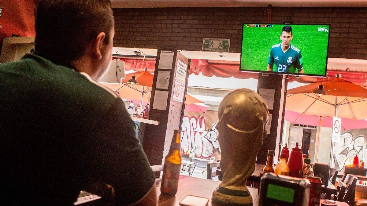 People gathered in a bar watching a soccer match on a large screen