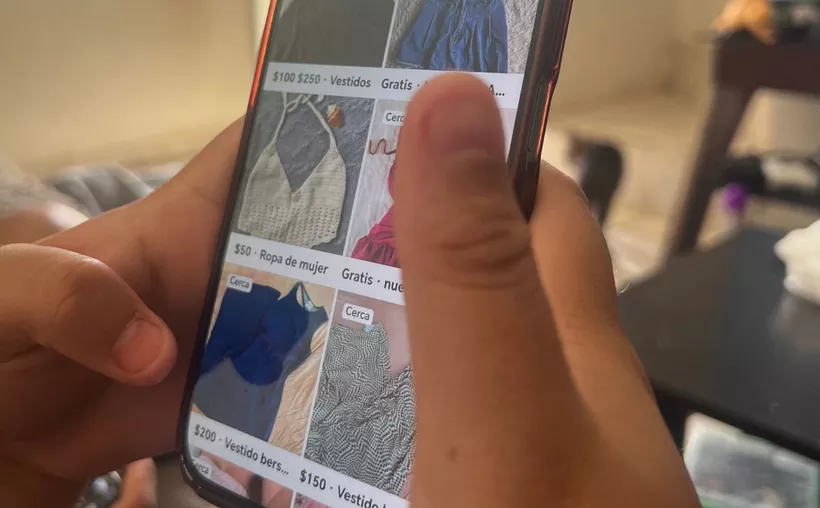 A person using a smartphone with social media icons and a warning symbol representing digital fraud in Cancun