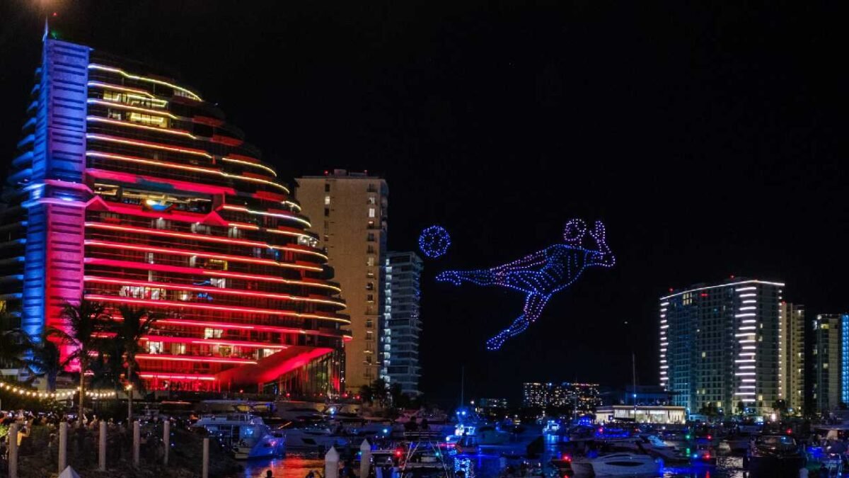 Thousands of drones forming a dolphin and the word Cancún in the night sky over Marina Puerto Cancún