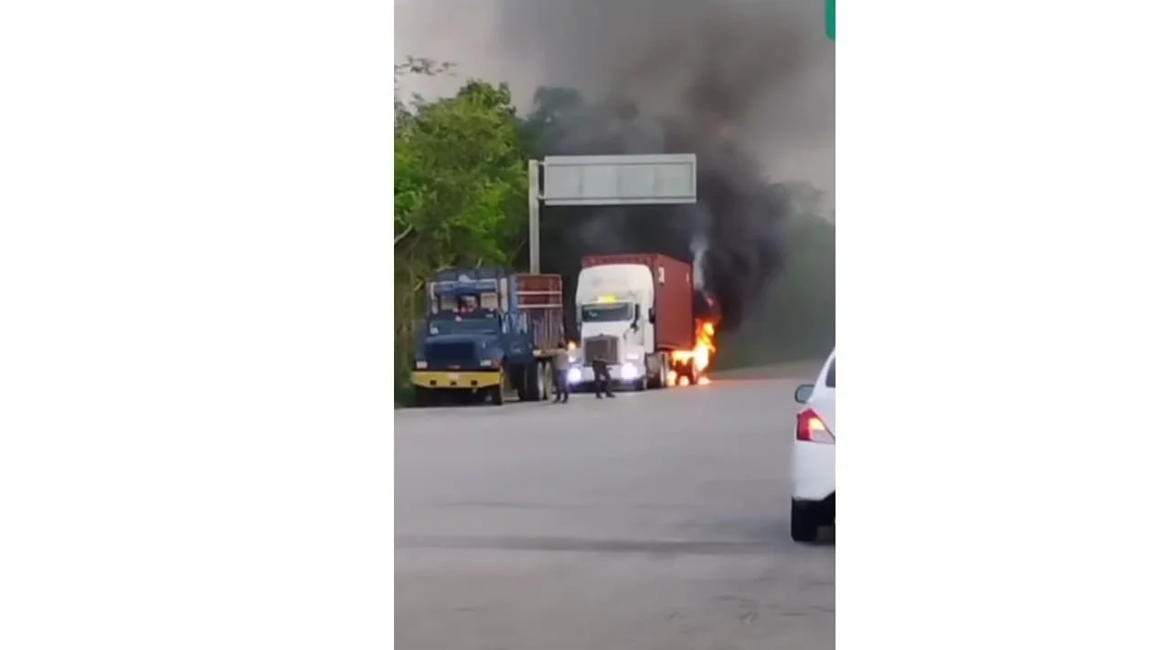 Firefighters battling a large chemical fire on a highway near Tulum, with thick red and black smoke rising