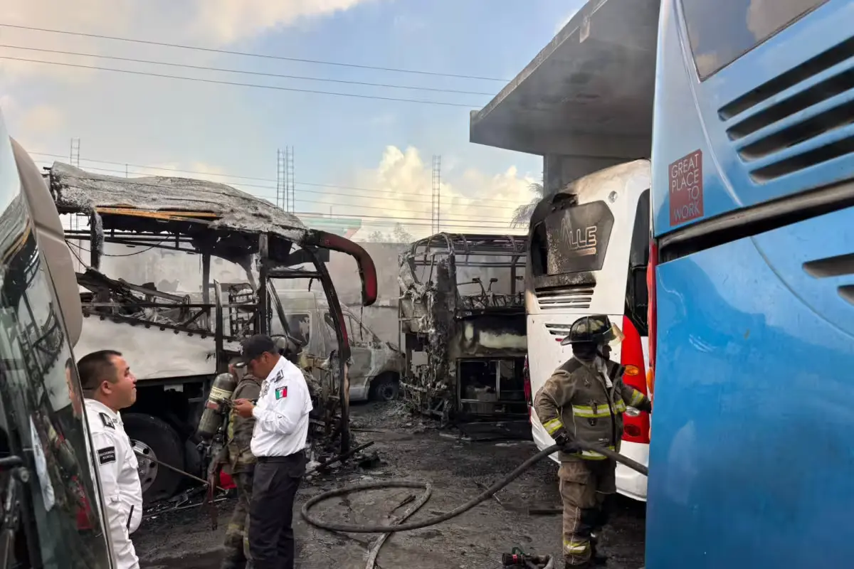 Firefighters spraying water on burning buses at Del Valle depot in Cancun