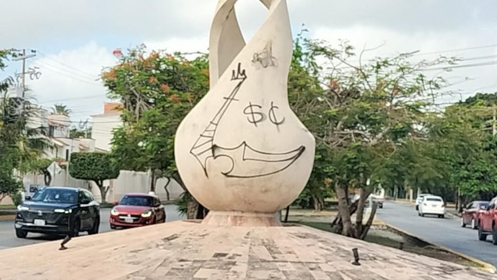 The deteriorated 'Gota de la Esperanza' sculpture covered in graffiti and peeling paint at a Cancun traffic circle.