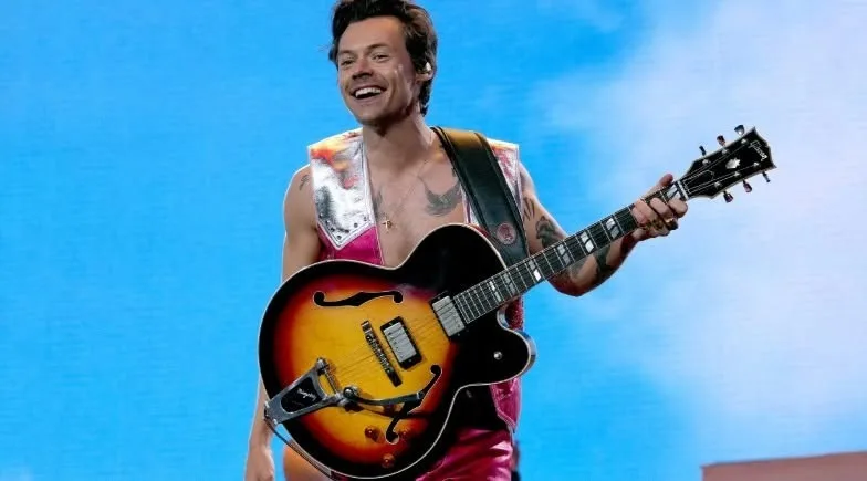 Harry Styles performing during a concert with colorful lights