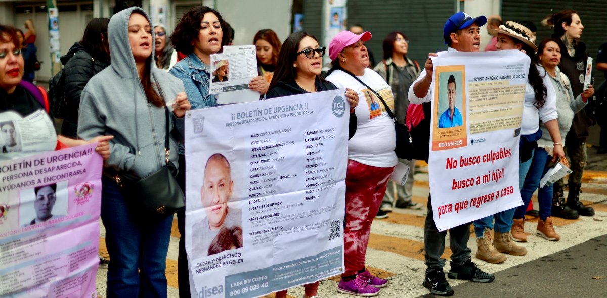 Mothers of disappeared persons protest outside Nemesio Diez stadium in Toluca, holding photos of their missing children.