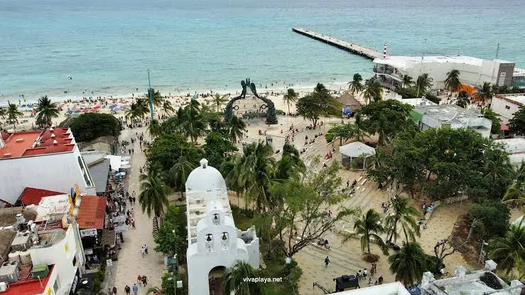 A street in Playa del Carmen with colorful buildings and palm trees, representing the proposed Barrio Mágico district.