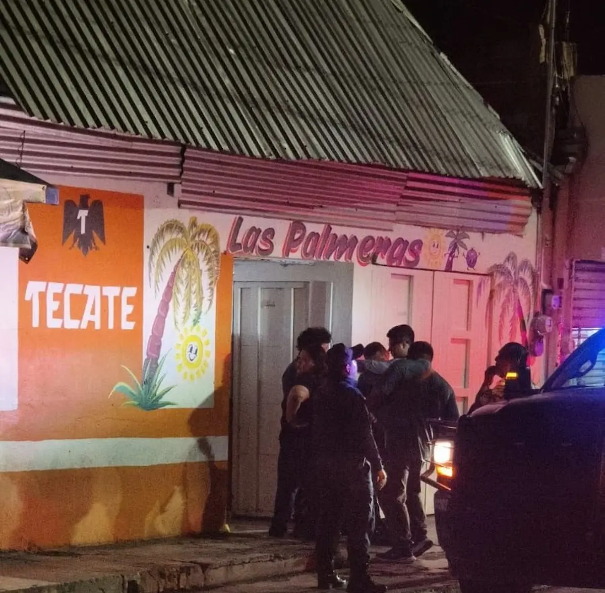 Police vehicles and officers block the street near Bar Las Palmas after a shooting in Playa del Carmen