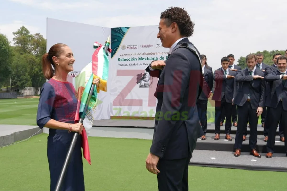 President Claudia Sheinbaum handing the Mexican flag to a player of the national soccer team during a ceremony at the National Palace.