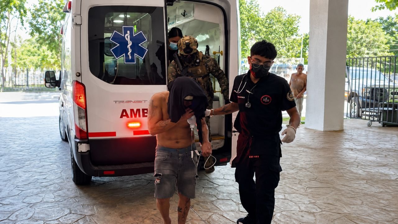 A rescued kidnapping victim being escorted by police officers at a hospital entrance in Cancun