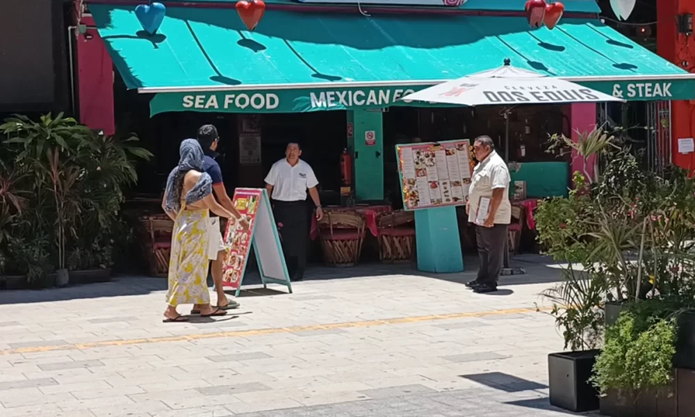 A restaurant in Playa del Carmen with a TV screen displaying a soccer match, illustrating the impact of FIFA broadcast fees on local businesses.
