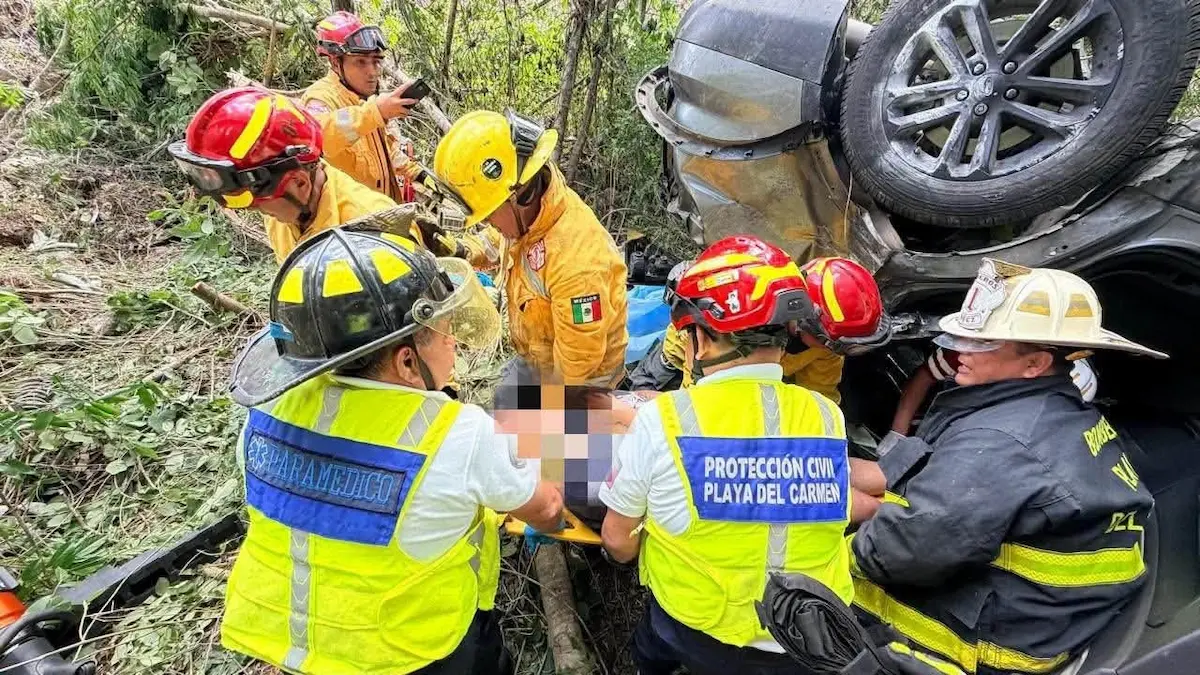 Rescue workers extricate a woman from an overturned vehicle on the Cancun-Playa del Carmen highway