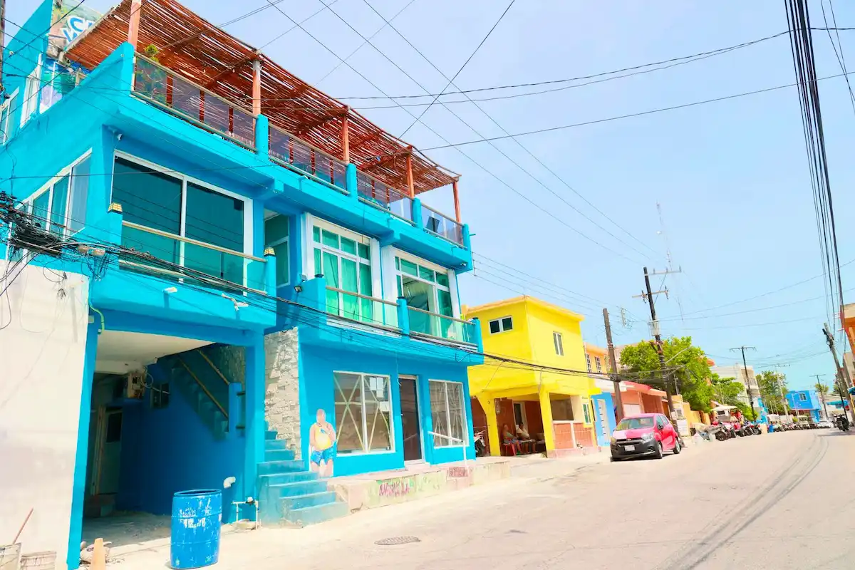 Workers painting colorful facades on a street in Isla Mujeres as part of the Rutas Mágicas de Color program