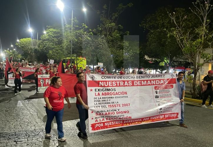 Teachers marching on Tulum Avenue in Cancun holding signs and banners