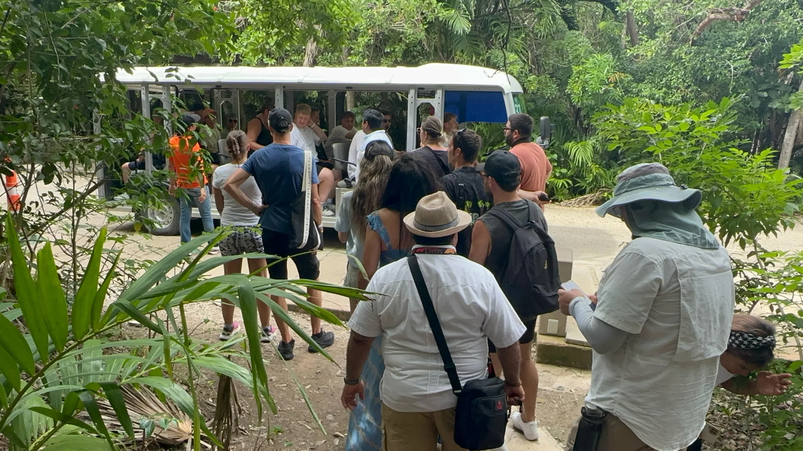 A small tourist train on a street in Tulum, surrounded by palm trees and buildings