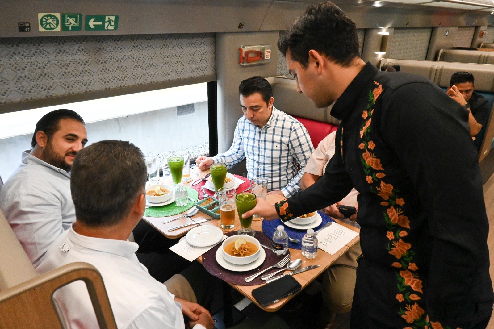 Interior of the Tren Maya's Janal restaurant car with plates of Yucatecan food on a table