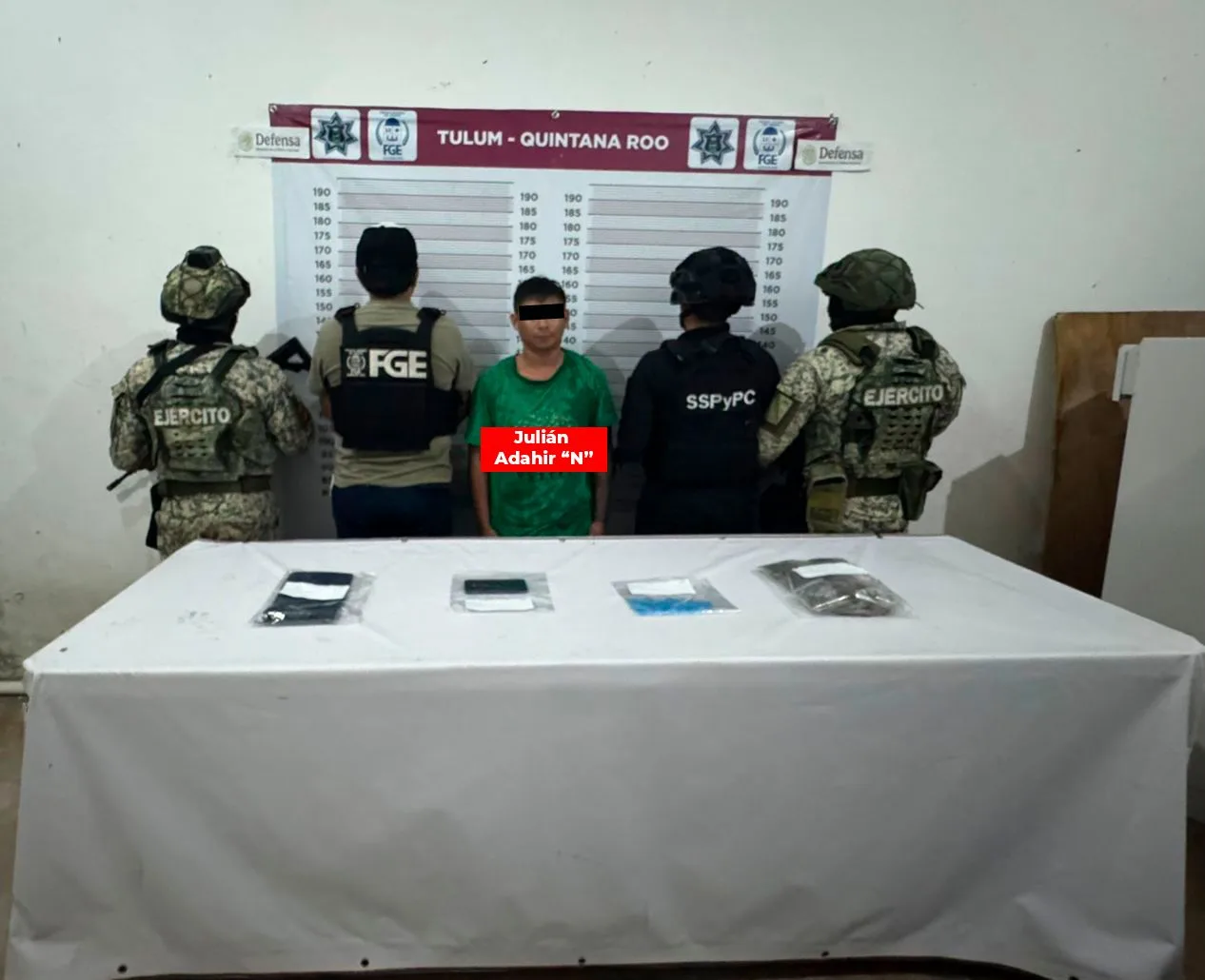 Three men in police custody with bags of seized drugs on a table