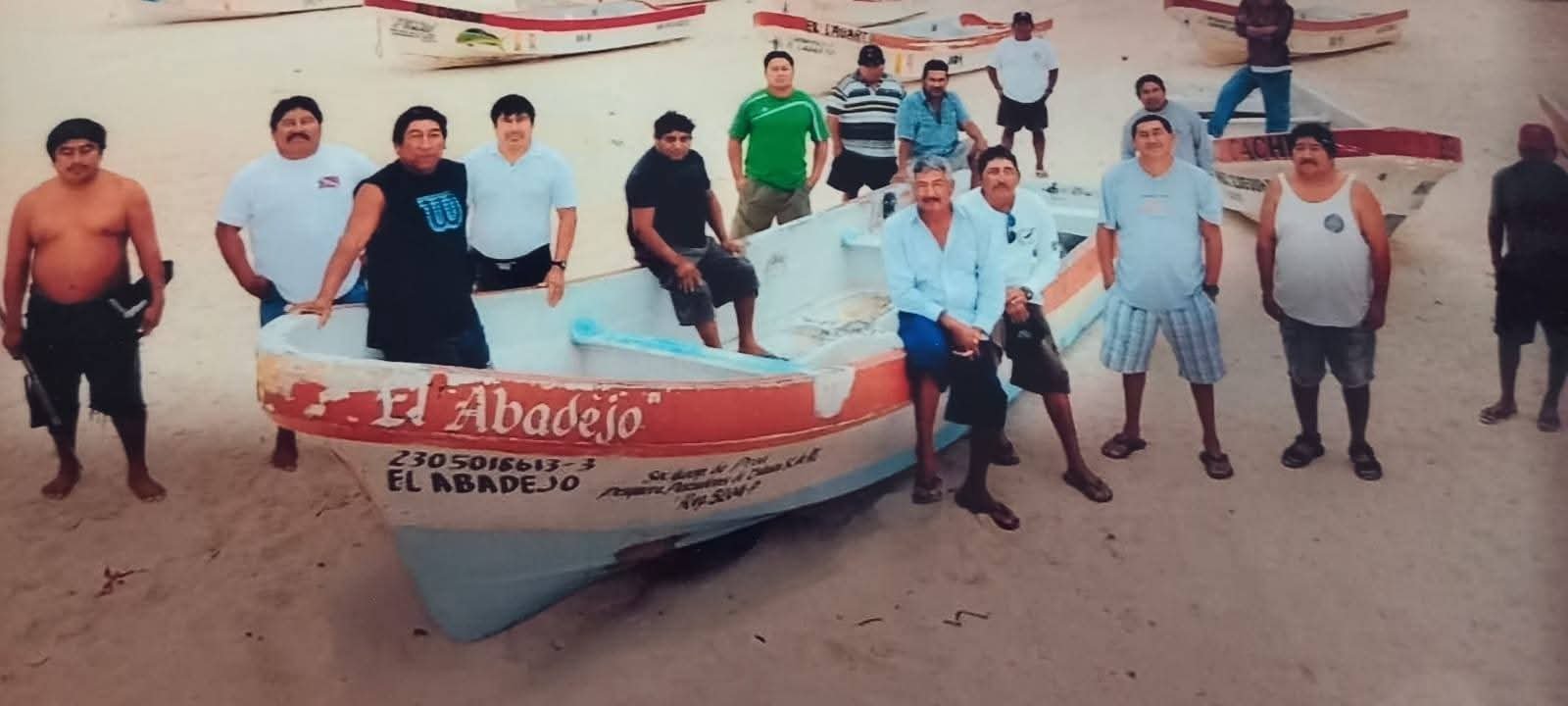 Members of the Pescadores de Tulum cooperative stand with their fishing boats on a beach in Tulum, Quintana Roo.
