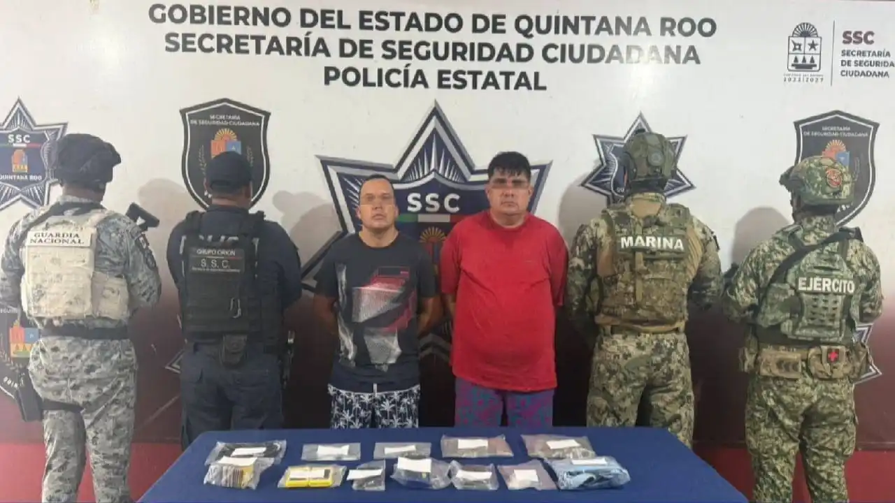 Two Venezuelan men in handcuffs being led by police officers in Cancun