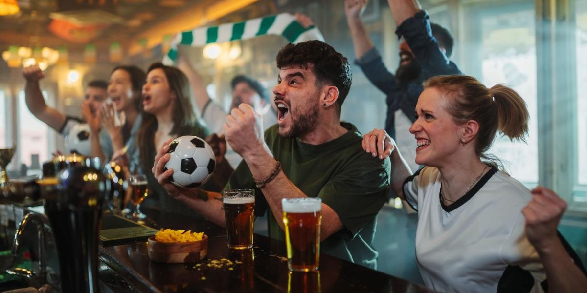 A bar showing a World Cup match on a large screen with customers watching