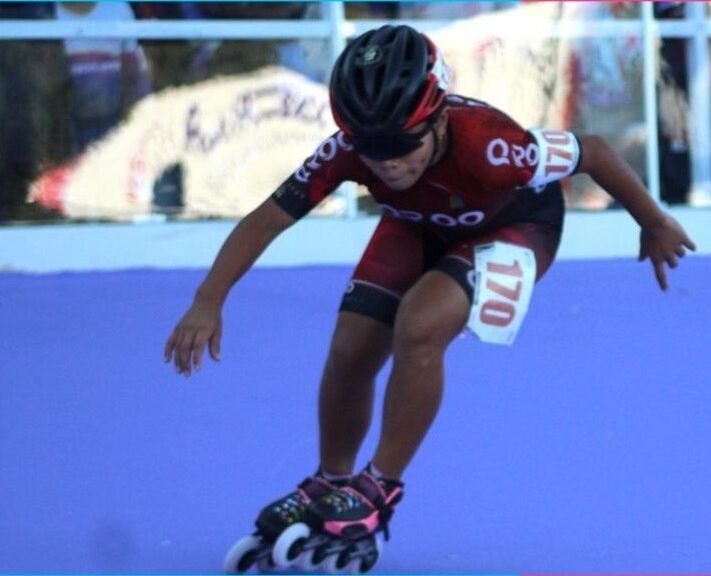 Young girl in roller skating gear holding five gold medals