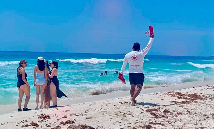 A beach in Cancún with warning flags and lifeguard station