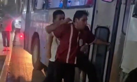Two men in bus driver uniforms fighting on a street in Cancun