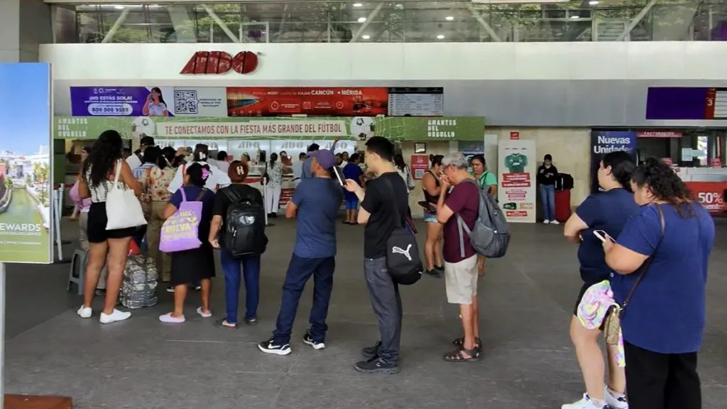 Passengers waiting in line at ticket counters inside Cancun bus terminal during summer vacation season