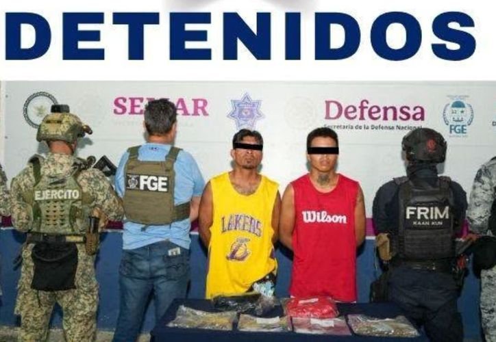 Two men in handcuffs being led by police officers in Cancun