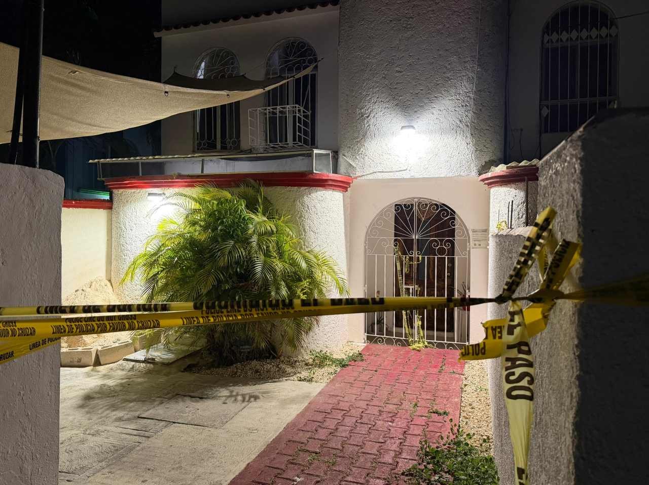 Police officers and forensic investigators at a home in Cancun where a woman's body was found buried in the patio