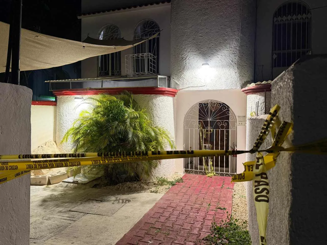 Police officers and forensic investigators at a home in Cancun where a woman's body was found buried in the patio