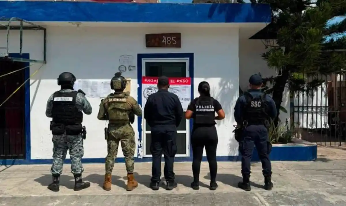 Police officers inspecting a seized vehicle and evidence bags during a raid in Chetumal, Quintana Roo