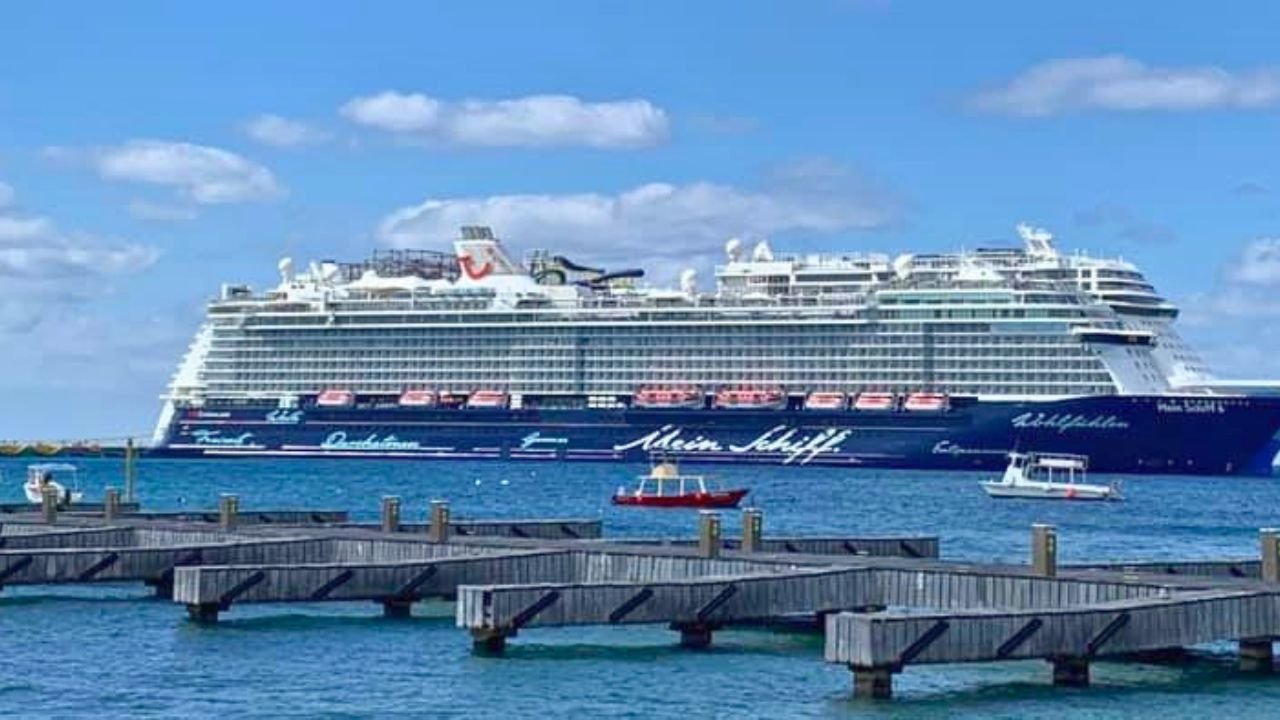 A large cruise ship docked at Cozumel's port with turquoise Caribbean waters in the background